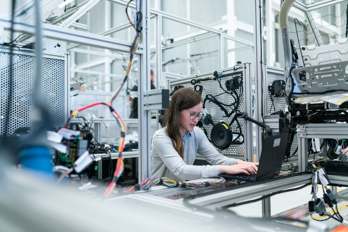 A technician working at an instrumented assembly bench on a factory floor.